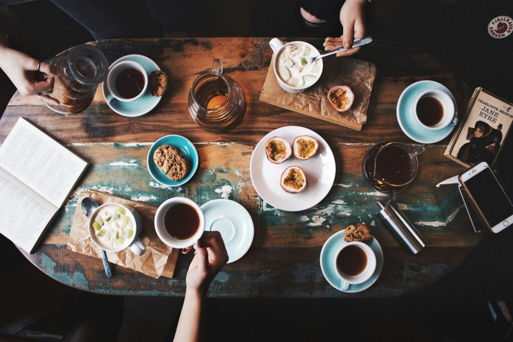 Vista aérea de uma mesa de centro aconchegante com xícaras, lanches e livros, perfeita para uma tarde relaxante.