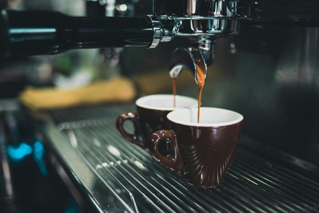 Close de uma máquina de café expresso profissional preparando café em xícaras.